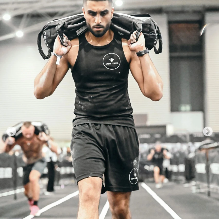 Anish Mehan carrying a sandbag at a Hyrox competition